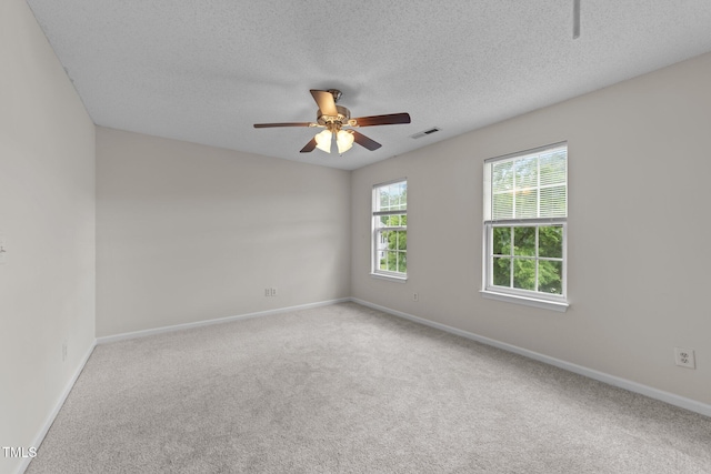 carpeted empty room with baseboards, a ceiling fan, visible vents, and a textured ceiling