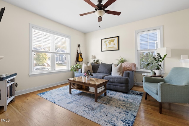 living area featuring baseboards, light wood-style flooring, and ceiling fan