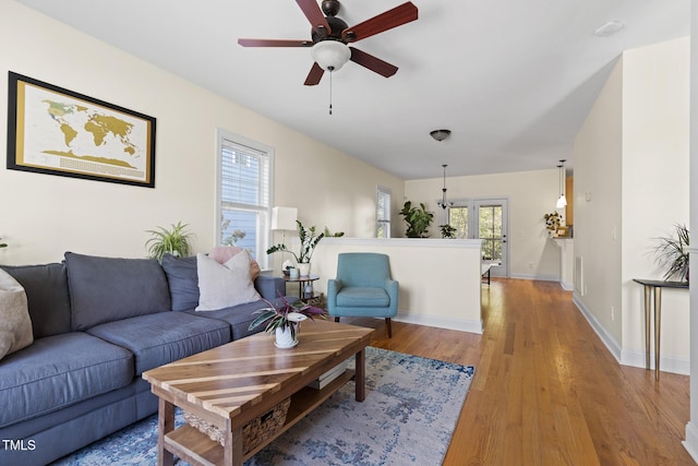 living room featuring light wood-type flooring, baseboards, and ceiling fan