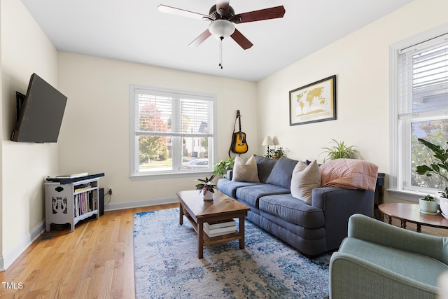 living room featuring baseboards, ceiling fan, a wealth of natural light, and light wood-style floors