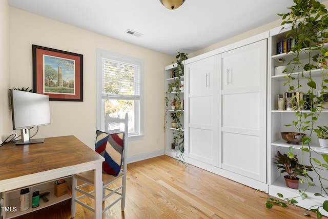home office featuring visible vents, light wood finished floors, and baseboards