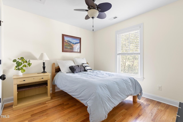 bedroom with baseboards, a ceiling fan, light wood-type flooring, and visible vents