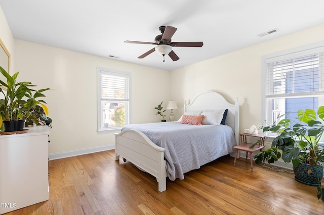 bedroom featuring visible vents, light wood-style floors, ceiling fan, and baseboards