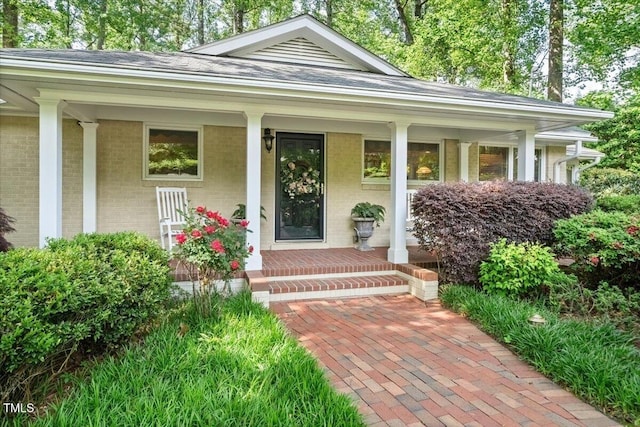 property entrance with covered porch and brick siding