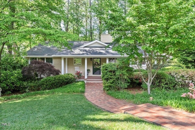 view of front facade featuring brick siding, a shingled roof, a front lawn, and covered porch