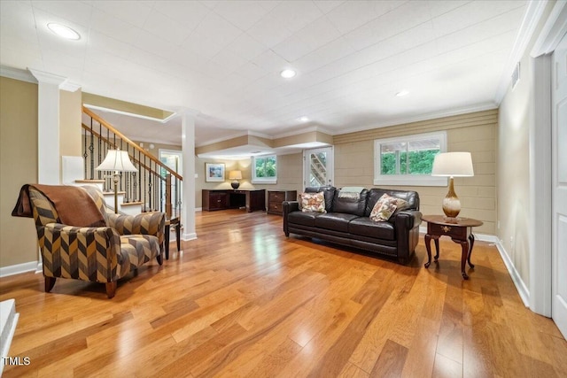 living room featuring light wood-type flooring, stairs, crown molding, and baseboards