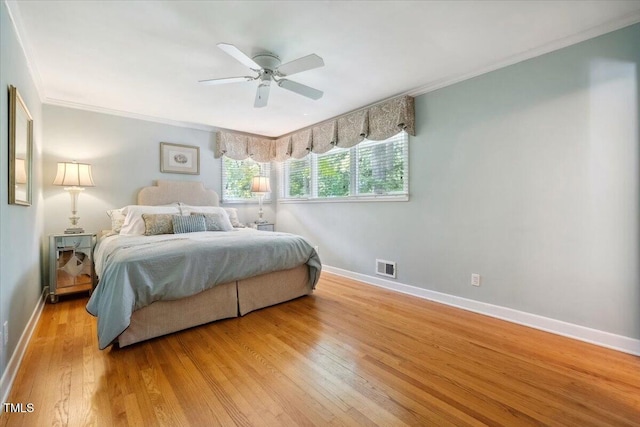 bedroom featuring ceiling fan, light wood-style flooring, baseboards, visible vents, and ornamental molding