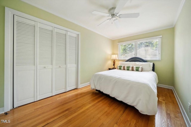 bedroom with a ceiling fan, light wood-type flooring, baseboards, a closet, and ornamental molding