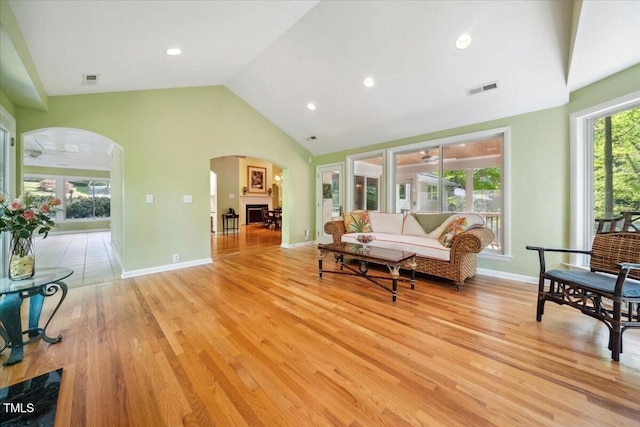 living area with visible vents, high vaulted ceiling, recessed lighting, arched walkways, and light wood finished floors
