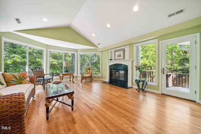 living room featuring light wood-type flooring, a premium fireplace, and visible vents