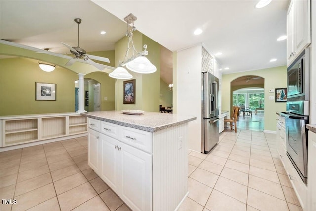 kitchen featuring arched walkways, appliances with stainless steel finishes, and light tile patterned flooring