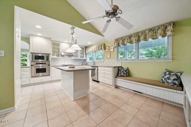 kitchen featuring appliances with stainless steel finishes, a center island, white cabinetry, backsplash, and vaulted ceiling