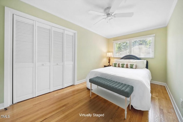 bedroom featuring a closet, ornamental molding, baseboards, light wood-style floors, and a ceiling fan