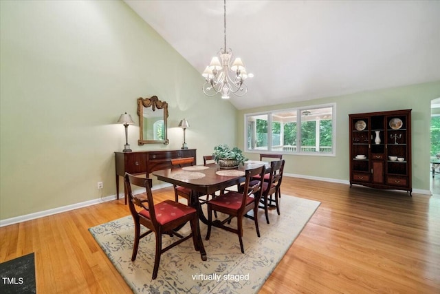 dining room with baseboards, high vaulted ceiling, wood finished floors, and a notable chandelier