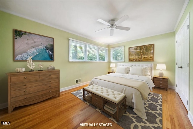 bedroom with visible vents, ornamental molding, baseboards, a ceiling fan, and light wood-style flooring