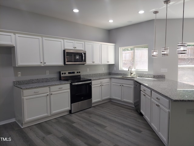 kitchen with dark wood-style flooring, a sink, white cabinets, a peninsula, and stainless steel appliances