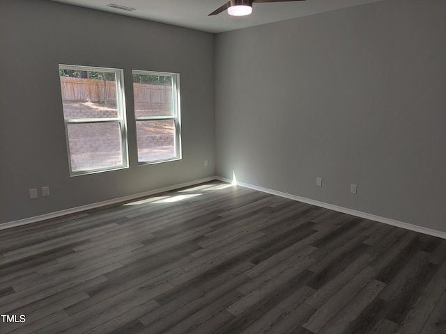 unfurnished room featuring baseboards, ceiling fan, dark wood finished floors, and visible vents