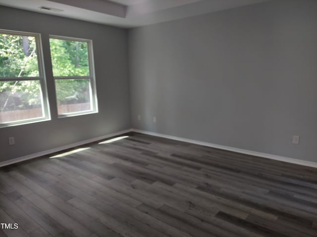 unfurnished room featuring baseboards and dark wood finished floors