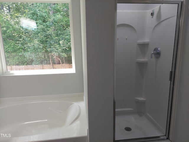 bathroom featuring a garden tub and a shower stall