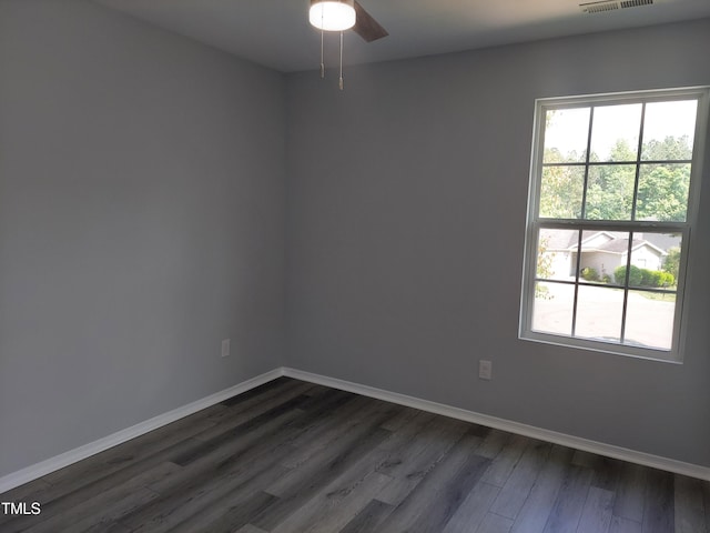 spare room with baseboards, a ceiling fan, dark wood-style flooring, and visible vents