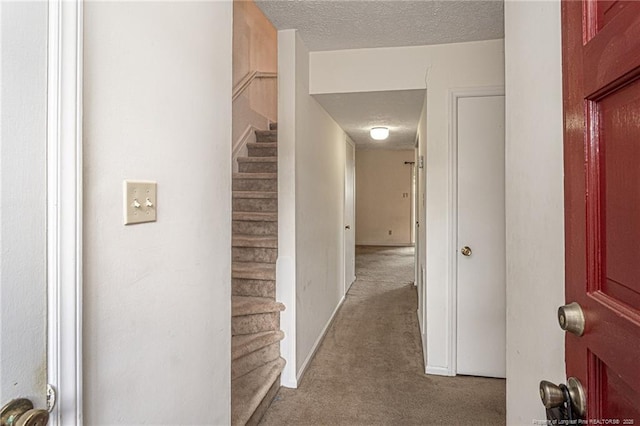 corridor with baseboards, carpet flooring, a textured ceiling, and stairway