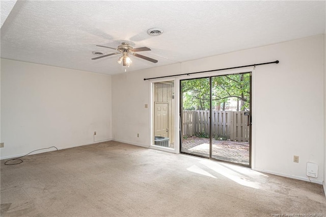 carpeted empty room with visible vents, a textured ceiling, baseboards, and ceiling fan