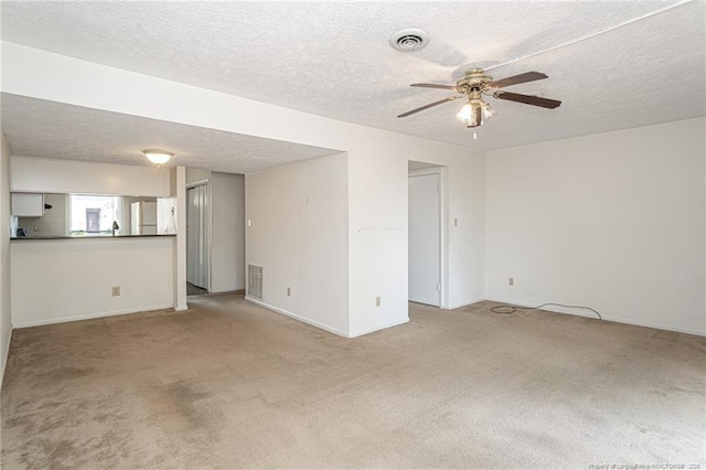 unfurnished living room with carpet floors, ceiling fan, a textured ceiling, and visible vents