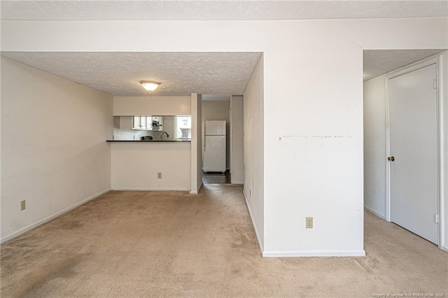 unfurnished living room featuring baseboards, light carpet, and a textured ceiling