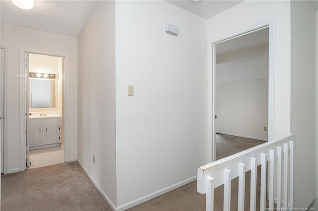 hallway featuring baseboards, carpet flooring, and a textured ceiling