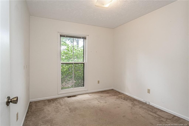 carpeted spare room featuring a textured ceiling, visible vents, and baseboards