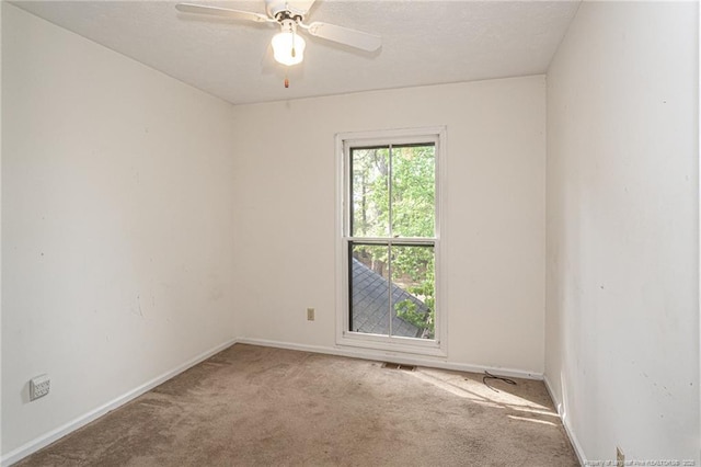 carpeted empty room featuring baseboards, visible vents, and ceiling fan