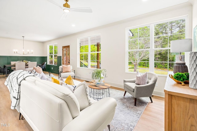 living area featuring light wood finished floors and ceiling fan with notable chandelier