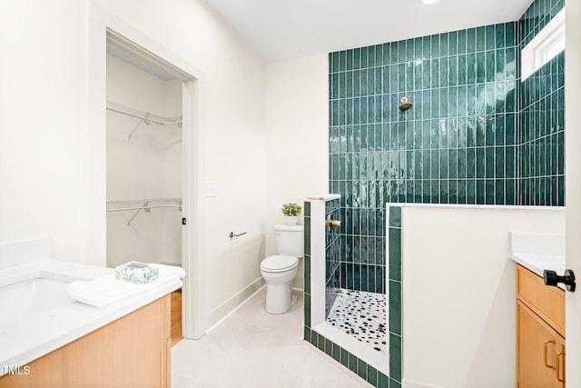 bathroom featuring vanity, a tile shower, toilet, and a walk in closet