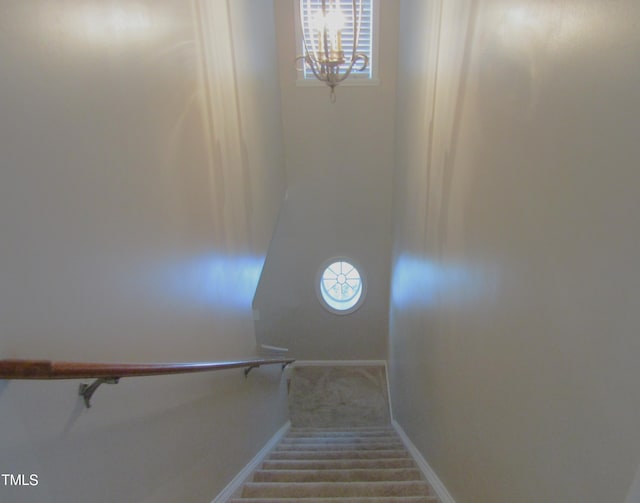 stairway with baseboards, carpet flooring, and a notable chandelier