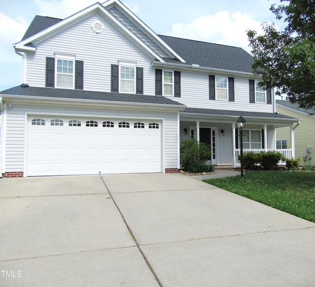 traditional home with an attached garage, concrete driveway, a porch, and a front yard