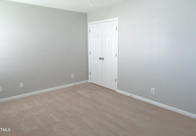 spare room with baseboards and light carpet