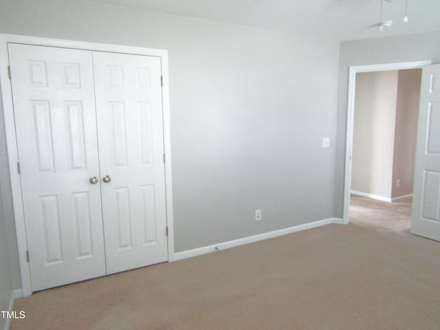 unfurnished bedroom featuring baseboards, a closet, and light carpet