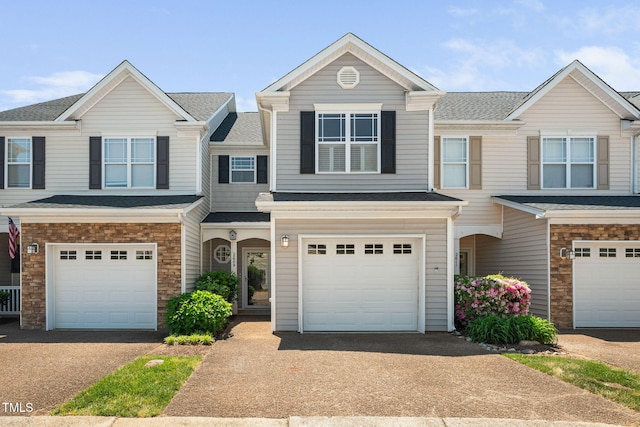 view of property with an attached garage, driveway, and a shingled roof