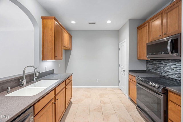 kitchen featuring visible vents, decorative backsplash, electric range oven, stainless steel microwave, and a sink