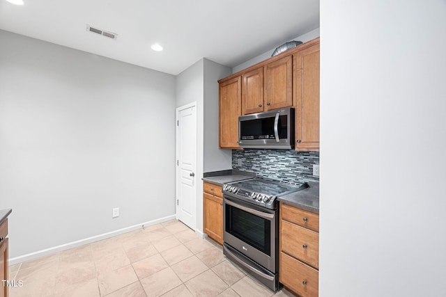 kitchen with backsplash, visible vents, dark countertops, baseboards, and stainless steel appliances