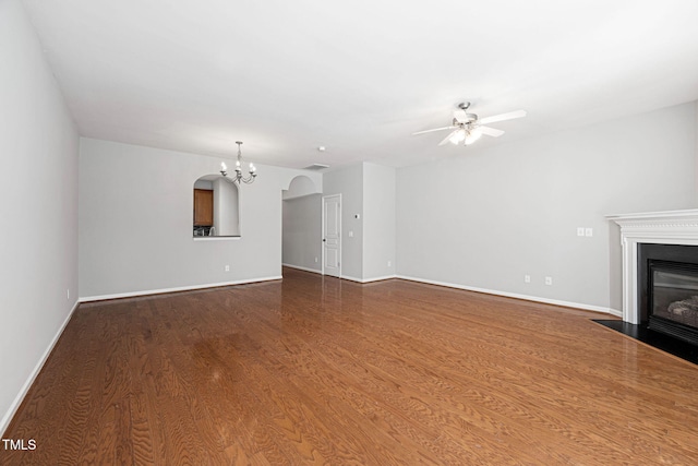 unfurnished living room with a fireplace with flush hearth, baseboards, ceiling fan with notable chandelier, and dark wood-style floors