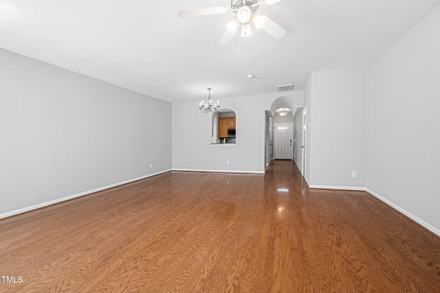 unfurnished living room with visible vents, arched walkways, wood finished floors, baseboards, and ceiling fan with notable chandelier