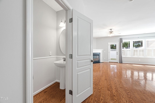 bathroom with baseboards, a ceiling fan, a fireplace with flush hearth, and wood finished floors