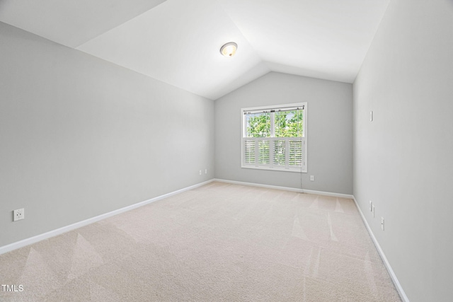 spare room with baseboards, light colored carpet, and lofted ceiling