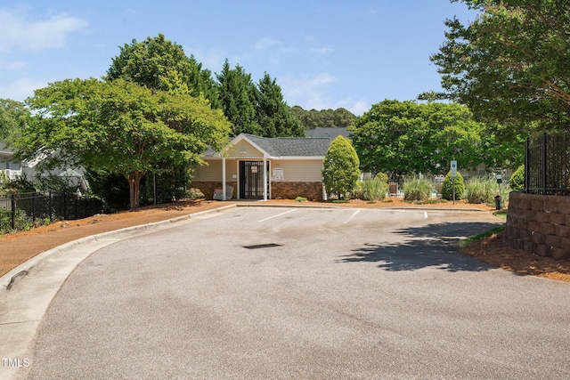 view of front of property with brick siding, fence, and uncovered parking