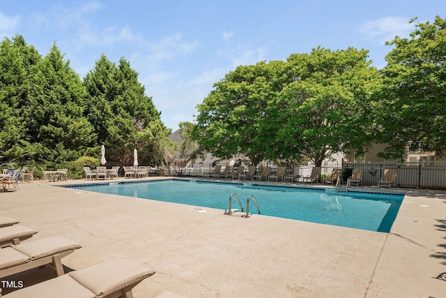 pool with a patio and fence