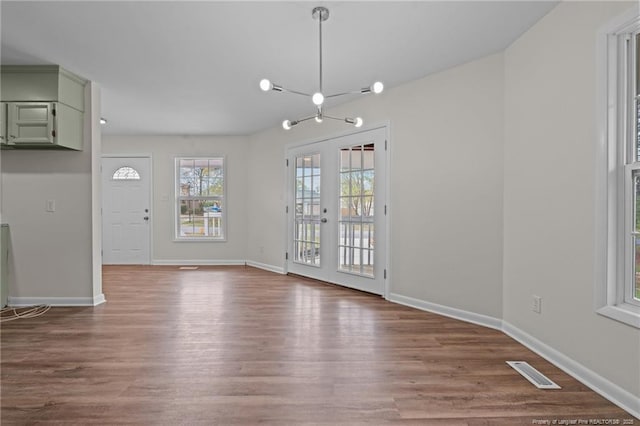 unfurnished dining area with french doors, baseboards, visible vents, and wood finished floors