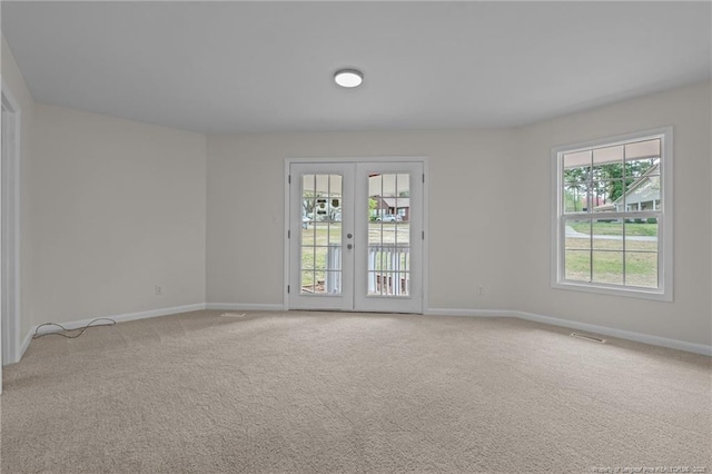 spare room featuring baseboards, visible vents, french doors, and light colored carpet