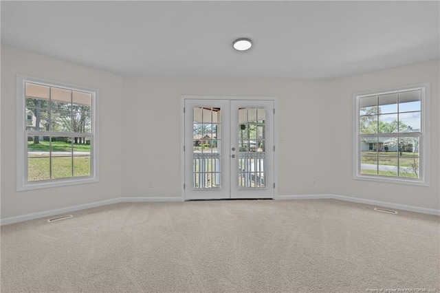 carpeted empty room featuring baseboards, visible vents, and french doors