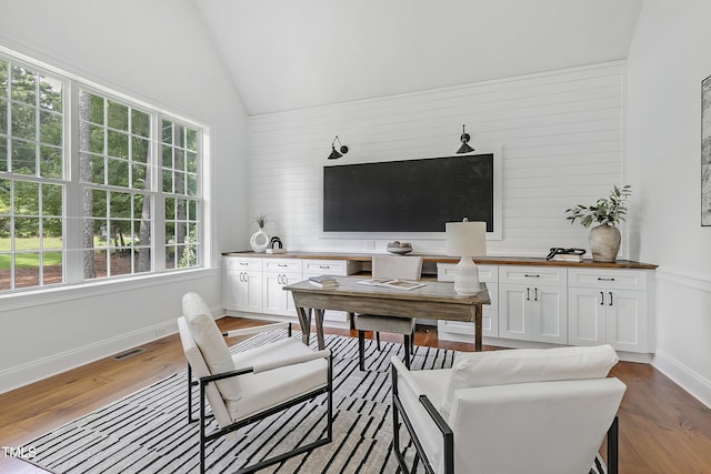 living area featuring visible vents, baseboards, lofted ceiling, and wood finished floors